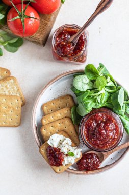 Domates reçeli, ziyafet ya da cam kavanozda kraker ve salata yapraklarıyla sos. Alışılmadık bir reçel. Akdeniz mutfağı. Üst görünüm.