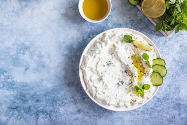 Hint veya Pakistan raita sosu veya salatalık, yoğurt, sarımsak ve nane, mavi beton arka plan. Geleneksel Hint mutfağı. Üst görünüm.