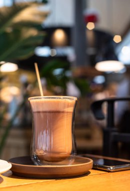 Sıcak çikolata ya da bardakta lokum bulunan kakao ya da ahşap masa, bulanık kafe arka planı. Tonu ayarlanmış resim.