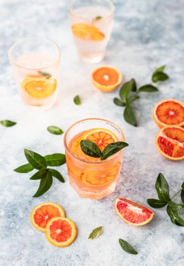 Sicilya portakallı cin ve tonik içki ve mavi beton arka planda buz. Soğuk ferahlatıcı kokteyl..