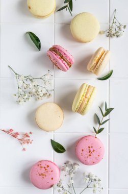 Fransız badem kurabiyelerinin pastel renkleri ve beyaz fayanslı çingene çiçekleri. Üst görünüm.