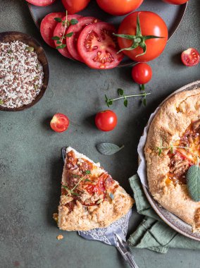 Baharatlı domates turtası, açık turta veya domatesli galet ve yeşil arka planda aromatik otlarla süslenmiş peynir..