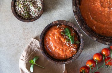 Kremalı ev yapımı domates çorbası, kızarmış ekmek ve çimento arka planında mikroyeşil kase. Üst görünüm.