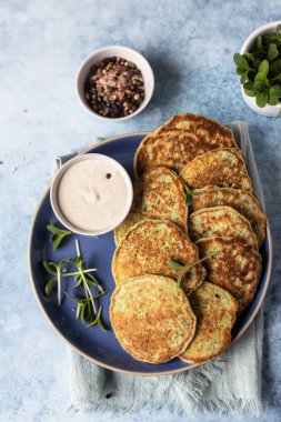 Sebzeli börek ya da kabaktan yapılmış krep, brokoli ya da mikroyeşil soslu ıspanak, mavi arka plan. Sağlıklı vejetaryen yemekleri. Üst görünüm.