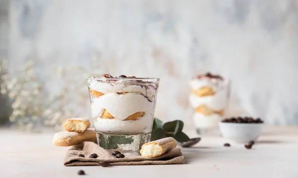 Traditionelles italienisches Desserttiramisu, Steinhintergrund. Portionsdessert mit Kaffeegeschmack aus Savoiardi und Mascarpone verziert mit Kakao und Kaffeebohnen. — Stockfoto