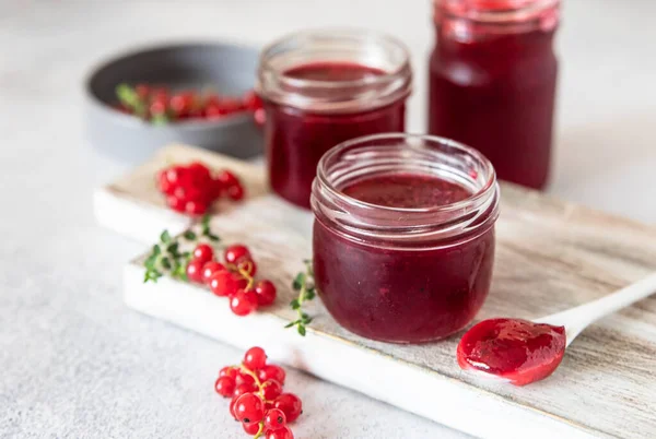 Marmellata di ribes rosso fatta in casa o gelatina in barattoli di vetro e frutti di bosco di ribes rosso. — Foto Stock