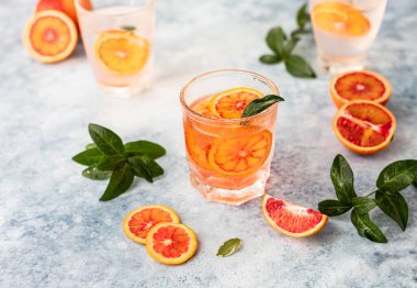 Sicilya portakallı cin ve tonik içki ve mavi beton arka planda buz. Soğuk ferahlatıcı kokteyl..