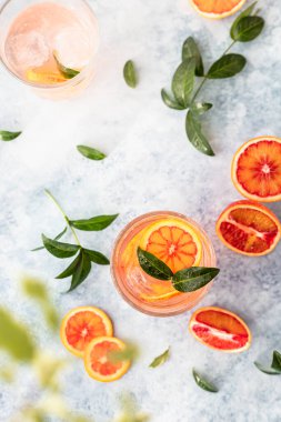 Sicilya portakallı cin ve tonik içki ve mavi beton arka planda buz. Soğuk ferahlatıcı kokteyl..