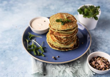 Bir yığın brokoli ya da yoğurtlu ıspanaklı krep ya da kremalı ekşi sos ve mikroyeşil, mavi beton arka plan. Vejetaryen börekleri. Sağlıklı yemek..