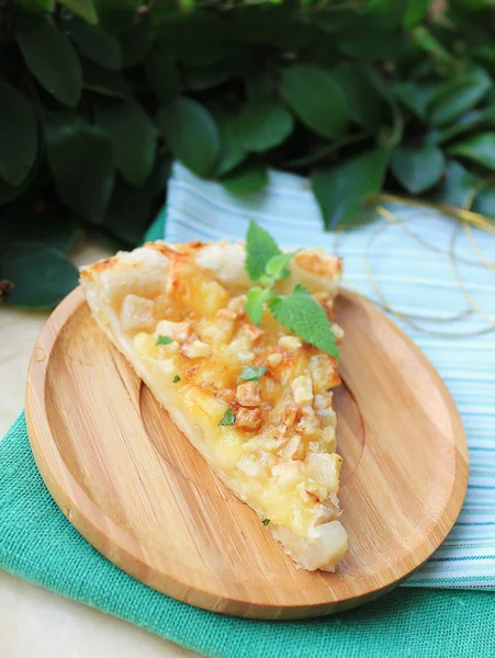 Slice of homemade puff pastry pie with camembert cheese, ripe pears and walnuts served with fresh organic mint for breakfast or summer picnic