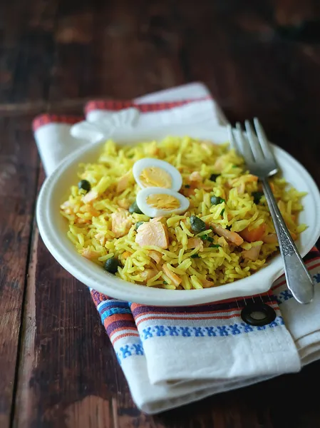 Traditional indian dish Kedgeree with cooked basmati rice, smoked salmon or trout fish, onion, garlic, milk, curry powder and served with hard-boiled eggs in a plate for lunch or dinner