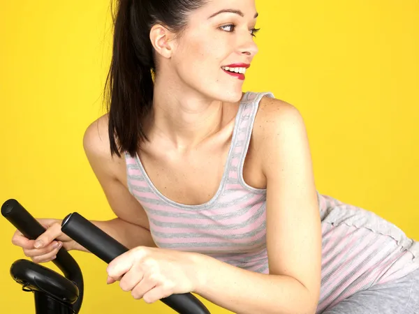 Mujer joven usando bicicleta de ejercicio — Foto de Stock