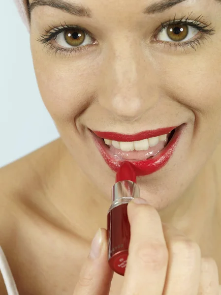 Mujer joven aplicando lápiz labial rojo —  Fotos de Stock