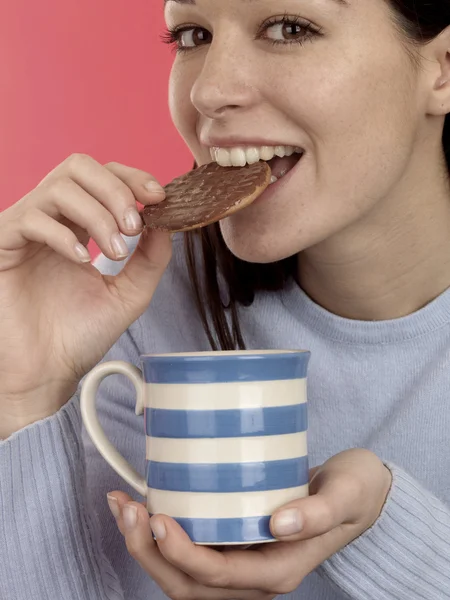 Ung kvinne som spiser kjeks. – stockfoto