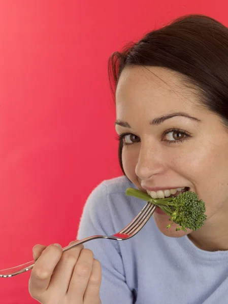 Jeune femme mangeant du brocoli tendon — Photo