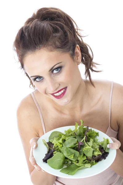Привлекательная молодая женщина ест салат с зелеными листьями — стоковое фото