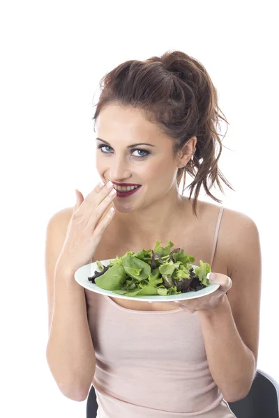 Привлекательная молодая женщина ест салат с зелеными листьями — стоковое фото