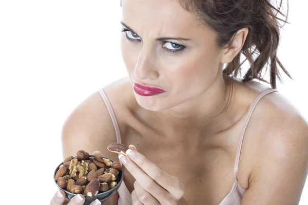 Atractiva mujer joven comiendo nueces mixtas —  Fotos de Stock