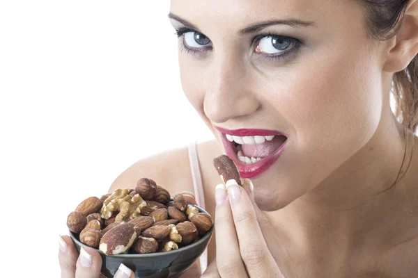 Atractiva mujer joven comiendo nueces mixtas —  Fotos de Stock