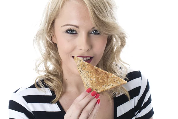 Mujer joven comiendo una rebanada de pan tostado — Foto de Stock