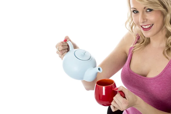 Jovem mulher atraente derramando chá de um bule — Fotografia de Stock