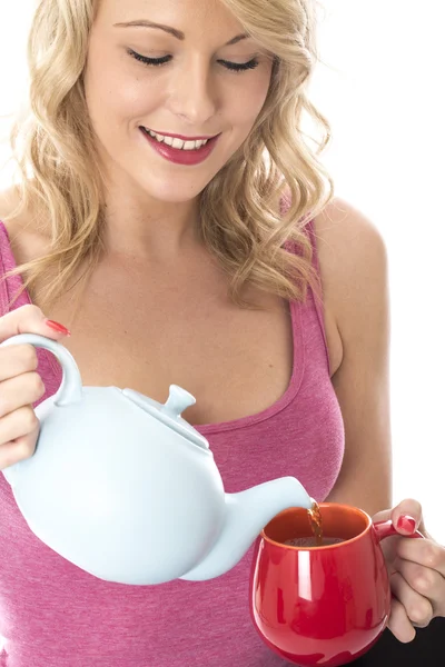 Aantrekkelijke jonge vrouw gieten thee uit een theepot — Stockfoto