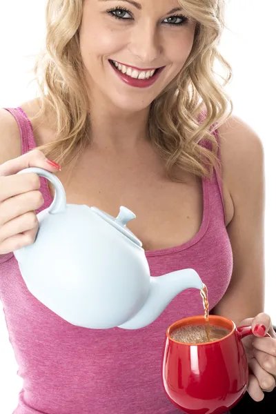 Aantrekkelijke jonge vrouw gieten thee uit een theepot — Stockfoto