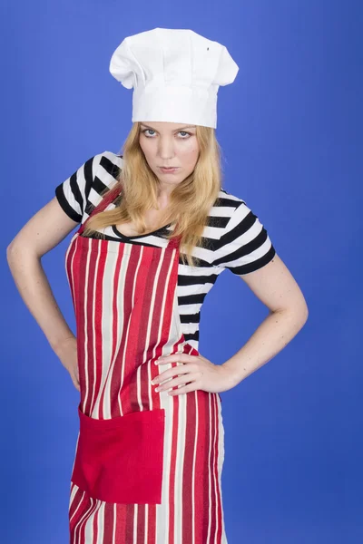 Zły młoda kobieta w kapeluszu kucharzy i fartuch — Zdjęcie stockowe