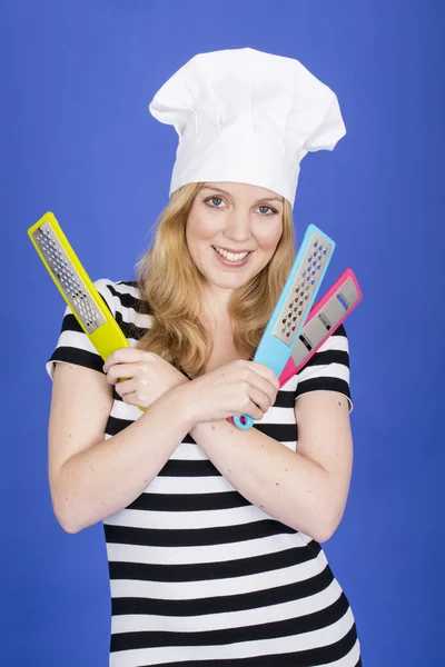 Jonge vrouw in chef-koks hoed, bedrijf keukengerei — Stockfoto