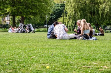 Epsom Surrey, Londra, Mayıs 09 2022, Çimenlerde oturan genç gruplar Dinleniyor ve konuşuyorlar