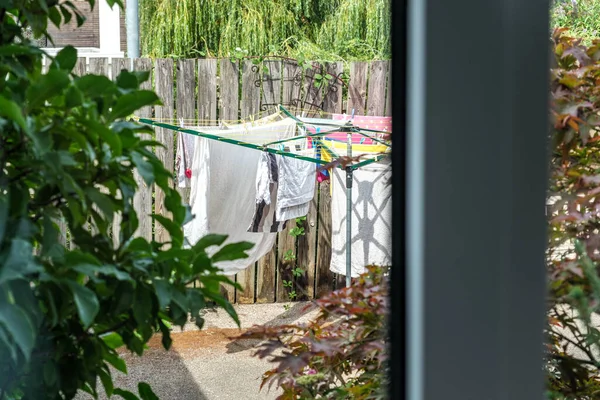 Dorking, Surrey Hills, London UK, August 14 2022, Drying Clothes On A Rotary Clothes Drier In A Back Garden Through Kitchen Window