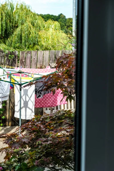 Dorking, Surrey Hills, London UK, August 14 2022, Drying Clothes On A Rotary Clothes Drier In A Back Garden Through Kitchen Window