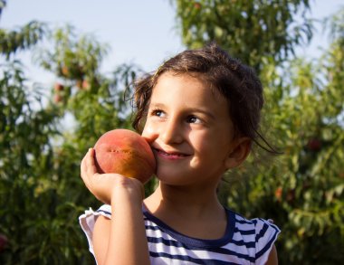 elinde bir şeftali ile küçük kız