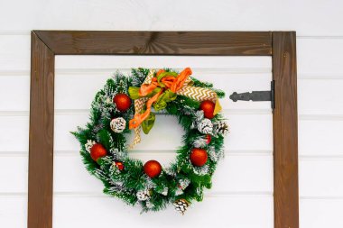 Kışın karlı şehir parkında Noel Baba 'nın evinin beyaz ahşap kapısı ve yapay çelenk yapısı. Noel Xmas yeni yıl tatili konsepti.