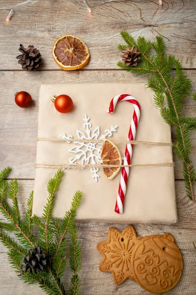 Schön verpackte Geschenkschachtel mit Tannenzweigen, Zuckerrohr, Dekor auf Holzgrund. Weihnachtsdekoration, Neujahr flach liegend, von oben flach, über Kopf — Stockfoto