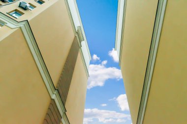 Mavi gökyüzü manzarasına karşı, şehrin yerleşim bölgesinde birbirine bitişik, yüksek binalı, sarı apartman binaları olan inşaat kompleksi. Gayrimenkul geliştirme.