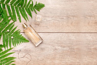 Cam şişedeki doğal kozmetik parfüm serumu, mücevher aksesuarları, yeşil eğreltiotu dallı ve fotokopi alanı olan ahşap arka plan. ekolojik ekoloji güzellik kavramı.