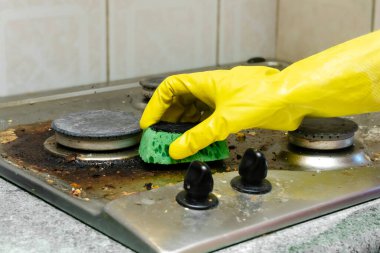 Kirli gaz sobasını yağdan temizlemek, yemek artıkları. Kadınlar koruyucu eldivenlerini sünger bezi ve deterjan ile mutfak sobasıyla veriyorlar. ev temizliği hizmeti kavramı