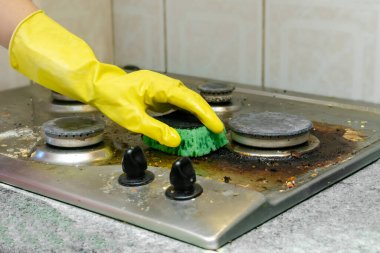Kirli gaz sobasını yağdan temizlemek, yemek artıkları. Kadınlar koruyucu eldivenlerini sünger bezi ve deterjan ile mutfak sobasıyla veriyorlar. ev temizliği hizmeti kavramı