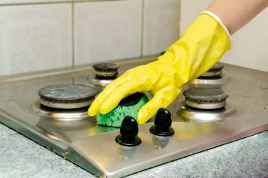 Kirli gaz sobasını yağdan temizlemek, yemek artıkları. Kadın eli koruyucu eldivende sünger bezi ve deterjan ile mutfak sobası yıkıyor. ev temizliği hizmeti kavramı.