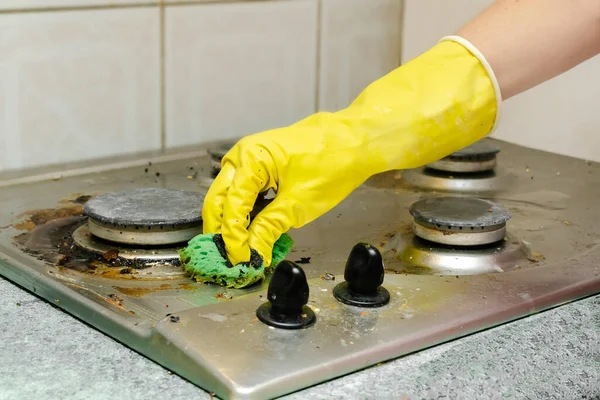 Kirli gaz sobasını yağdan temizlemek, yemek artıkları. Kadınlar koruyucu eldivenlerini sünger bezi ve deterjan ile mutfak sobasıyla veriyorlar. ev temizliği hizmeti kavramı