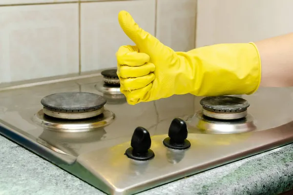 Cleaning dirty gas stove from grease, food leftovers deposits. womans hand in protective glove washing kitchen stove. home cleaning service concept — Stock Photo, Image
