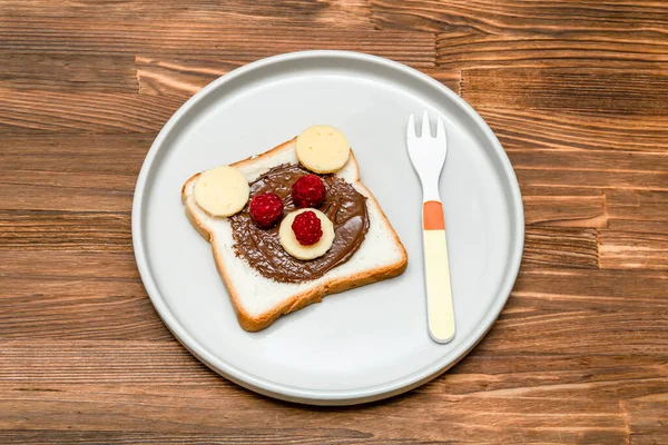 Drôle d'ours visage pain grillé sandwich avec beurre d'arachide, fromage et framboise sur fond en bois fermer. Enfants enfant dessert sucré déjeuner nourriture déjeuner — Photo