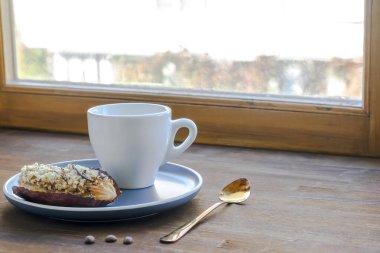 beyaz espresso kahve fincanı, taze pişmiş ekler mutfak masasında cam kenarında tatlı tabağı bulaşık takımı, süt sürahisi, ev yapımı yeşil bitki. Sabah kahvaltısı, fotokopi alanı