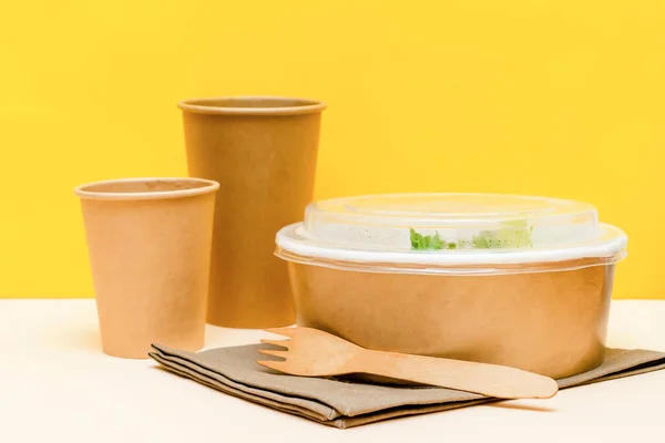 Healthy food lunch in kraft paper carton eco friendly box disposable bowl packaging container, cups on yellow background. chicken, eggs, greens. Take away delivery. environment protection.