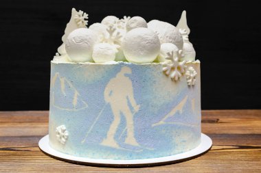 Beyaz mavi hindistan cevizi lezzetli vanilyalı kremalı pasta büyük yuvarlak marşmelov, çikolata kar taneleri, köknar ağaçları, dağ ve kayak resmi, ahşap masa üzerindeki tatlı tatlı tatlı tatlı