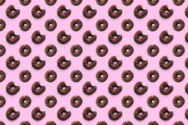 Czarny gryzione pączki z czerwoną glazurą na różowym tle bezszwowy wzór widok z góry. Jedzenie deser płasko położyć pyszne słodkie przekąski pączki czekoladowe — Zdjęcie stockowe
