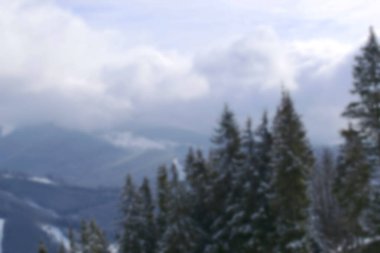 Karlı dağların ve çam ormanlarının kışın güneşli doğa manzarasının, köyün, kış sporlarının, tatilin bulanık ve seçici bir odak noktası..