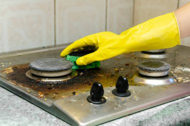 Kirli gaz sobasını yağdan temizlemek, yemek artıkları. Kadınlar koruyucu eldivenlerini sünger bezi ve deterjan ile mutfak sobasıyla veriyorlar. ev temizliği hizmeti kavramı