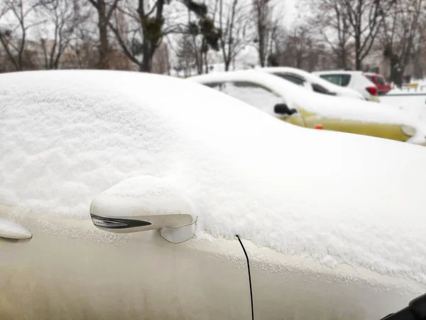 Snow layer on windscreen, window of sedan in city street driveway parking lot spot. car stuck after heavy blizzard snowfall snowstorm in winter. Snowdrifts and vehicle in extreme weather conditions — Stock Photo, Image